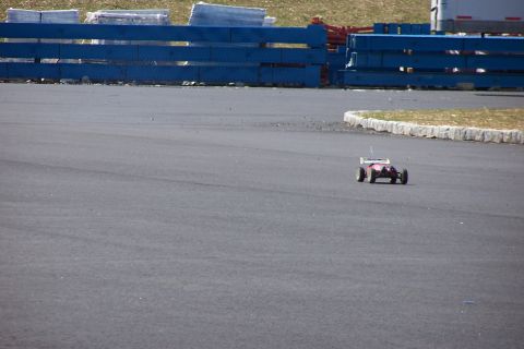 1994 Ford Bronco - A radio-controlled car is seen on a paved track with blue barriers in the background.