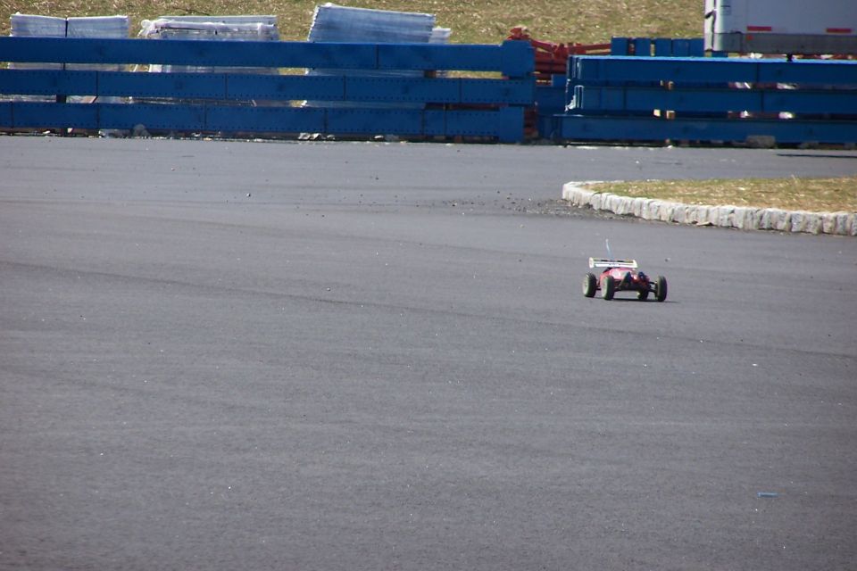 Radio-controlled car with pink body and green wheels on an asphalt track