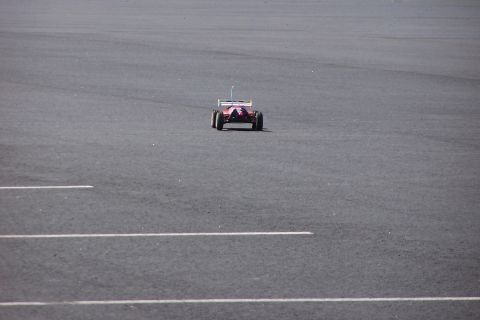 1994 Ford Bronco - A small radio-controlled car is seen from the rear on a paved surface with white lines.
