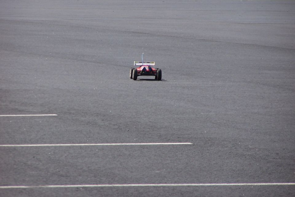 Red radio-controlled car with white spoiler on asphalt