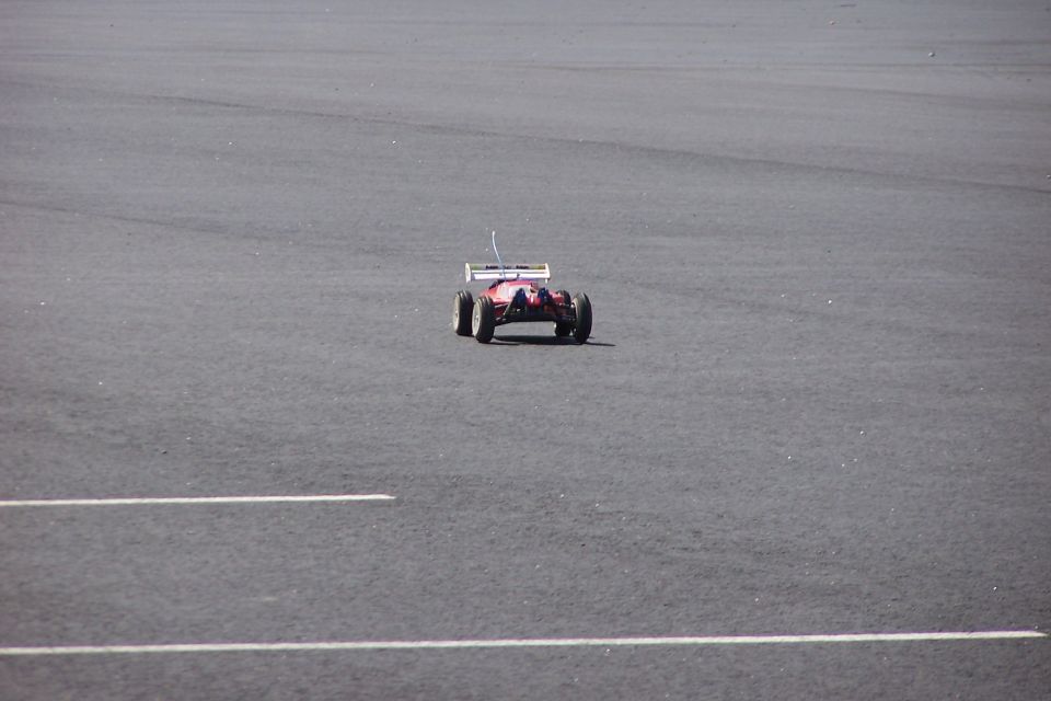 Red remote control car on asphalt with white lines