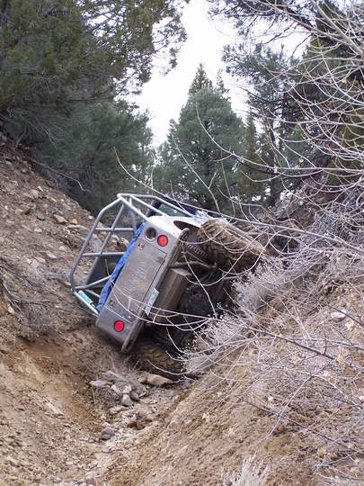 1986 Ford Bronco - Off-road vehicle with roll cage rolled onto its side in a ditch.