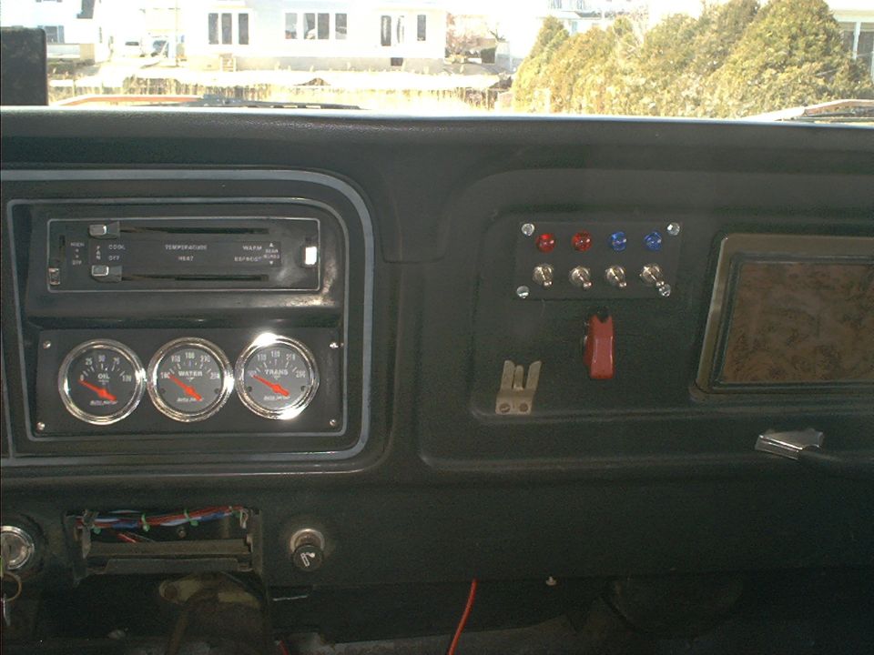 1978 Ford Bronco interior showing aftermarket gauges and a panel of switches