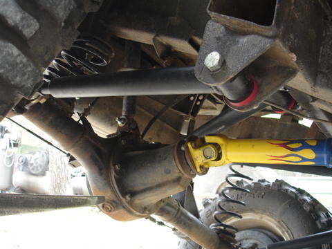 1987 Ford Bronco - Close-up view of the undercarriage of a heavily modified off-road vehicle, highlighting its drivetrain and suspension.