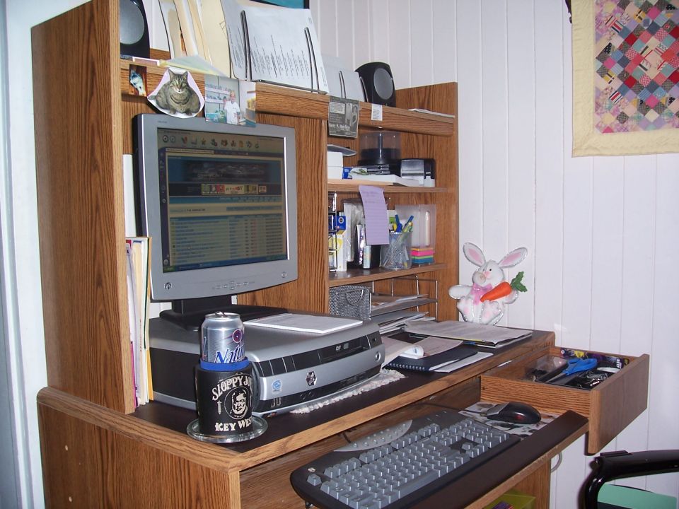 Desk with computer monitor, keyboard, printer, and office supplies. A can of beer is on the desk