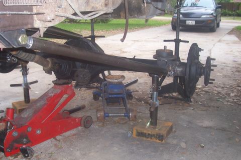 1987 Ford Bronco - Vehicle axle and suspension components are supported by jack stands during work.