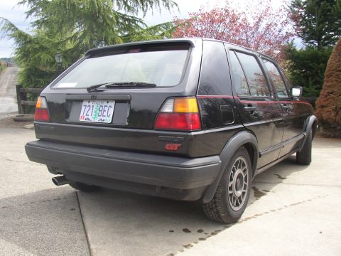 1987 Volkswagen Golf - The rear of a black 1987 Volkswagen Golf GT hatchback is shown from a 3/4 angle.