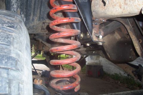 1987 Ford Bronco - Detail of the suspension system, focusing on the coil spring and surrounding frame components.