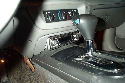 1999 Ford Crown Victoria - Interior center console view showing an aftermarket single-DIN car stereo mounted below the gray HVAC control panel with rotary dials, plus…