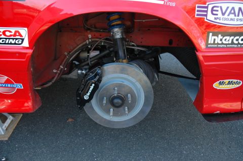 1993 Ford Mustang - Front wheel and brake assembly of a red race car with racing decals.