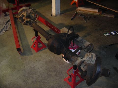 1991 Ford Bronco - A vehicle's front axle assembly is supported by jack stands in a garage setting.