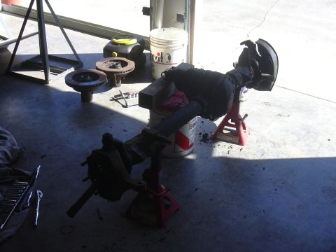 1991 Ford Bronco - Front axle assembly, likely from a truck or SUV, is disassembled and supported by jack stands.