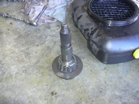 1991 Ford Bronco - A disassembled axle shaft and bearing sit on a concrete floor next to an oil drain pan.