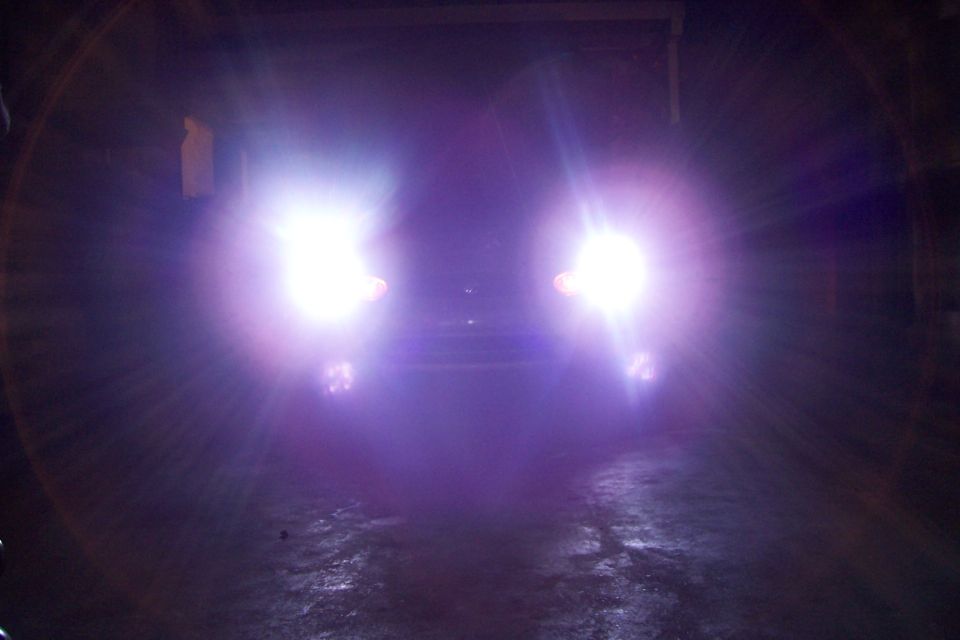 Car's headlights on, showing a purple glow. The vehicle is facing forward
