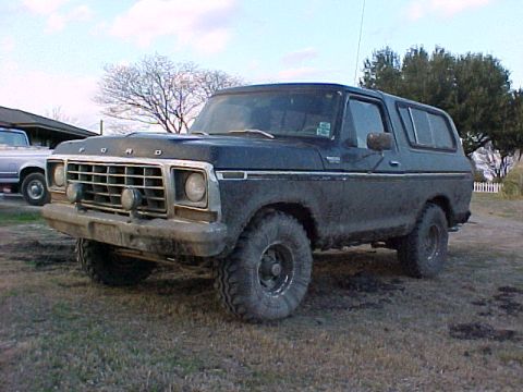 1978 Ford Bronco - A 1978 Ford Bronco is seen from a three-quarter front angle, parked on a dirt and grass lot.