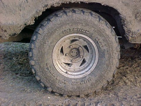 1978 Ford Bronco - Mud-covered off-road tire and wheel on a vehicle.