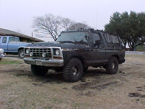 1978 Ford Bronco - This muddy 1978 Ford Bronco is parked in a dirt lot next to a blue pickup truck.