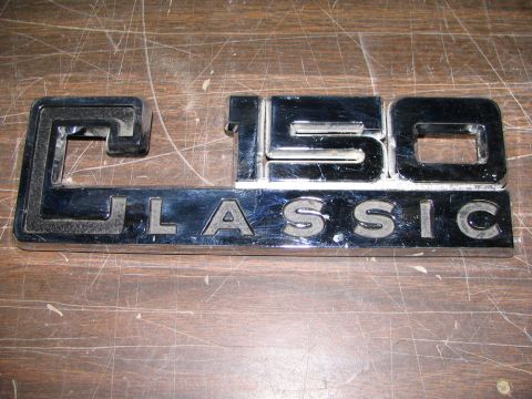 1993 Ford C-350 (Centurion Conversions) - A chrome emblem with the text "C150 CLASSIC" is shown against a wooden surface.