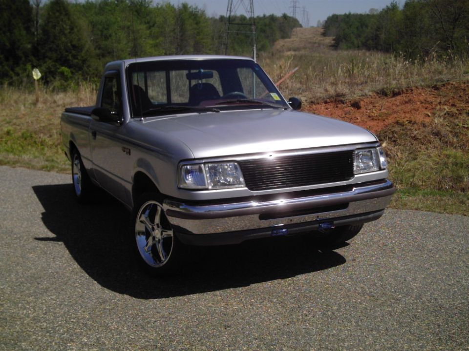 Silver 1990s Ford Ranger pickup with billet grille and chrome wheels