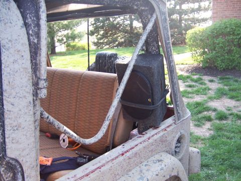 1998 Jeep TJ - Interior view of a mud-covered Jeep, aftermarket audio equipment and worn tan seats.