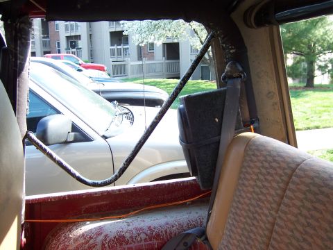 1998 Jeep TJ - View from inside a Jeep shows other vehicles parked in front of apartment buildings.