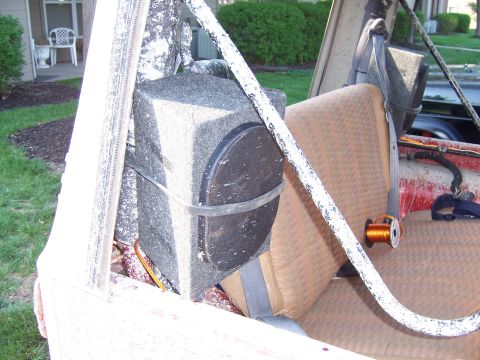 1998 Jeep TJ - The interior of a vehicle reveals a large speaker and tan seats, with a white roll bar visible.