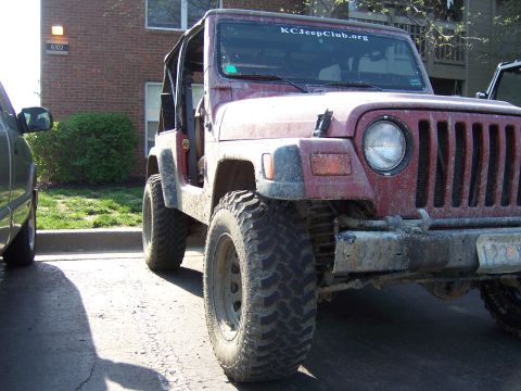 1998 Jeep TJ - This Jeep Wrangler is parked in front of a brick building, with a second vehicle to its left.