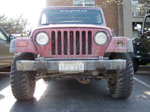 1998 Jeep TJ - Front view of a red Jeep Wrangler, possibly modified, with a sticker on the windshield.