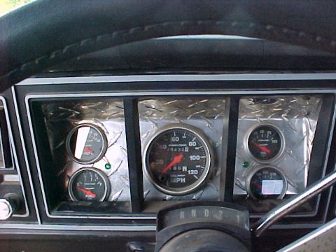 1978 Ford Bronco - Aftermarket gauges installed in a vehicle's dashboard, showing speed, fuel, and oil pressure.