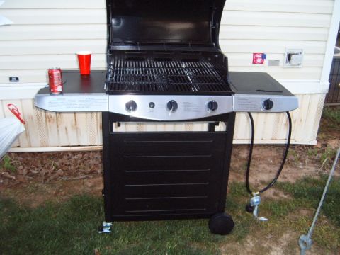 1988 Ford Bronco - A black gas grill with three burners sits on a grassy lawn next to a house.