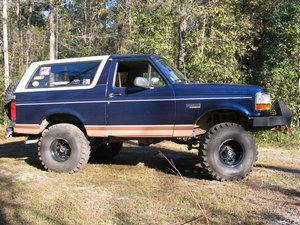 2004 Ford F-150 - This modified blue SUV, likely a 1996 Ford Bronco, features a white top and large off-road tires, suggesting it's built for terrain.