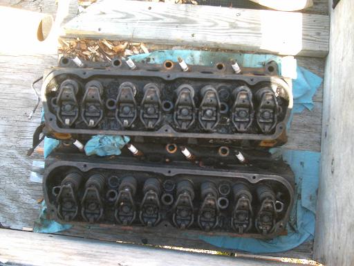 Two engine cylinder heads with spark plugs visible, resting on blue cloth