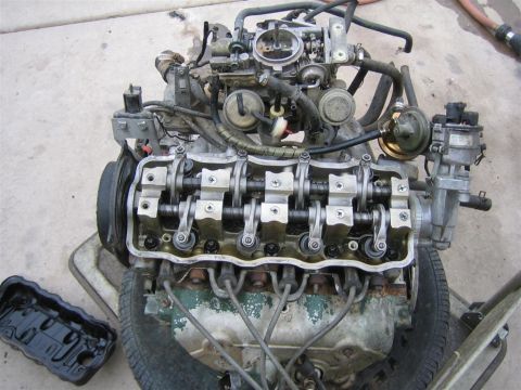 1987 Suzuki Samurai - Close-up view of an engine's internal components, including the camshaft and valve train, with external fuel and ignition systems attached.