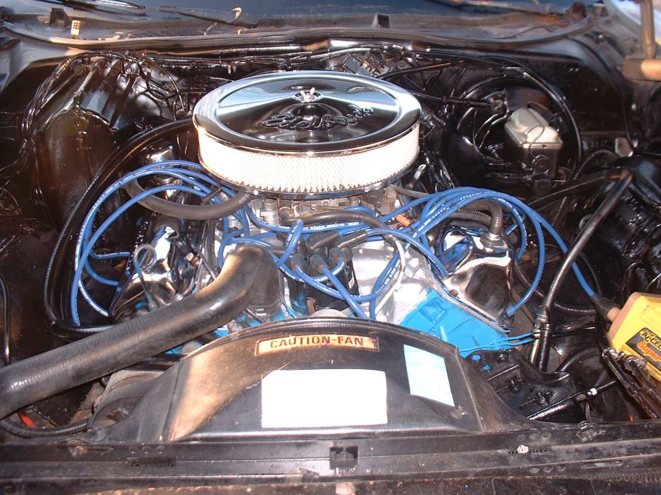 Engine bay with chrome air cleaner, blue spark plug wires, and a "CAUTION - FAN" sticker