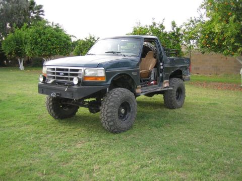 1994 Ford Bronco - Modified 1994 Ford Bronco parked on grass, showing off its lifted suspension and large off-road tires.