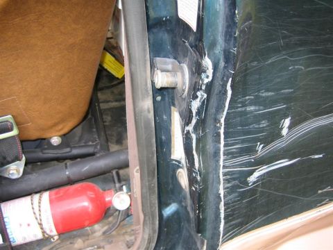 1994 Ford Bronco - The door jamb shows significant damage, including deep scratches and bent metal, with a fire extinguisher mounted nearby.