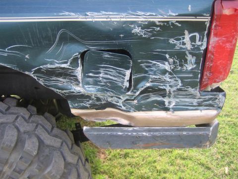 1994 Ford Bronco - This SUV's rear quarter panel shows severe damage, including deep scratches and a heavily dented bumper.