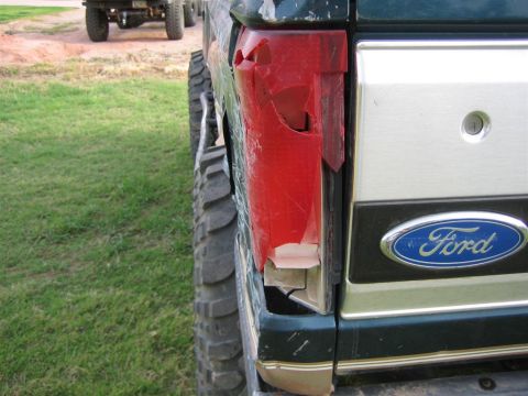 1994 Ford Bronco - The rear driver side taillight of a 1994 Ford Bronco is heavily damaged, with the Ford emblem visible nearby.