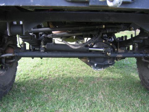 1994 Ford Bronco - Close-up of vehicle's front axle and suspension components, with grass in the background.