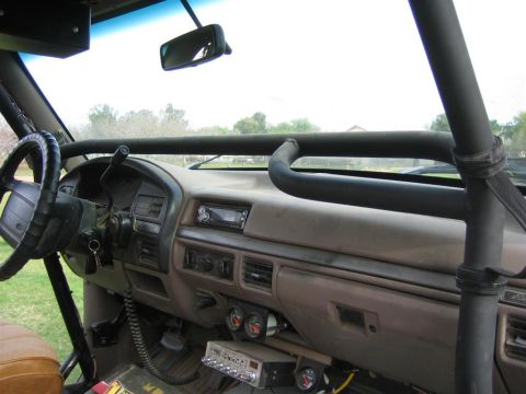 1994 Ford Bronco - The interior of a modified vehicle features a roll cage, CB radio, and auxiliary gauges, suggesting off-road use.