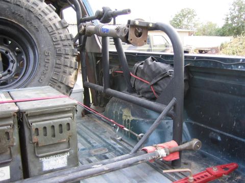 1994 Ford Bronco - Spare tire and roll cage installed in the bed of a pickup truck, with ammo cans secured.