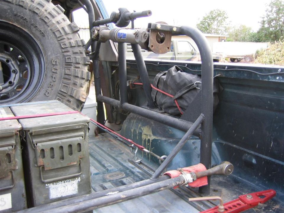 Truck bed with tube rack holding spare tire, driveshaft, ammo cans and hi-lift jack
