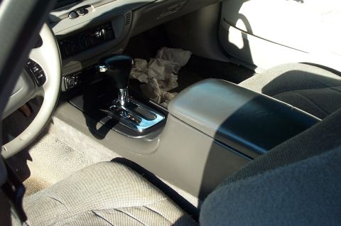 1999 Ford Crown Victoria - Interior view of the center console area showing a black leather-wrapped automatic shifter with chrome accents, tan/gray console trim, and…
