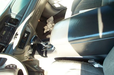 1999 Ford Crown Victoria - Interior view of a car showing the center console with a black leather-wrapped automatic shifter in the console-mounted position, the dashb…