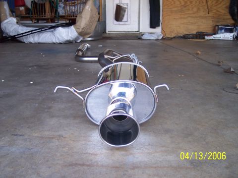1995 Ford Probe - A shiny exhaust system component rests on a garage floor, with other items in the background.
