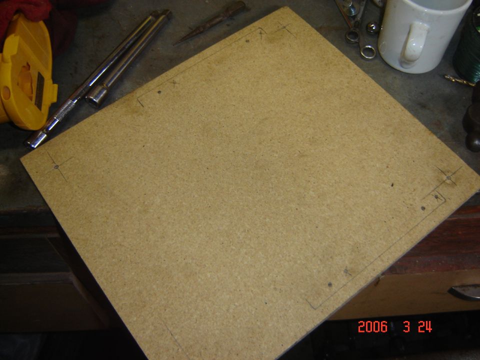 Particle board with pencil lines and corner markings, on a workbench with tools