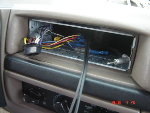 1993 Ford Bronco - The dashboard of a car shows an empty stereo slot with exposed wiring and a radio removal tool.