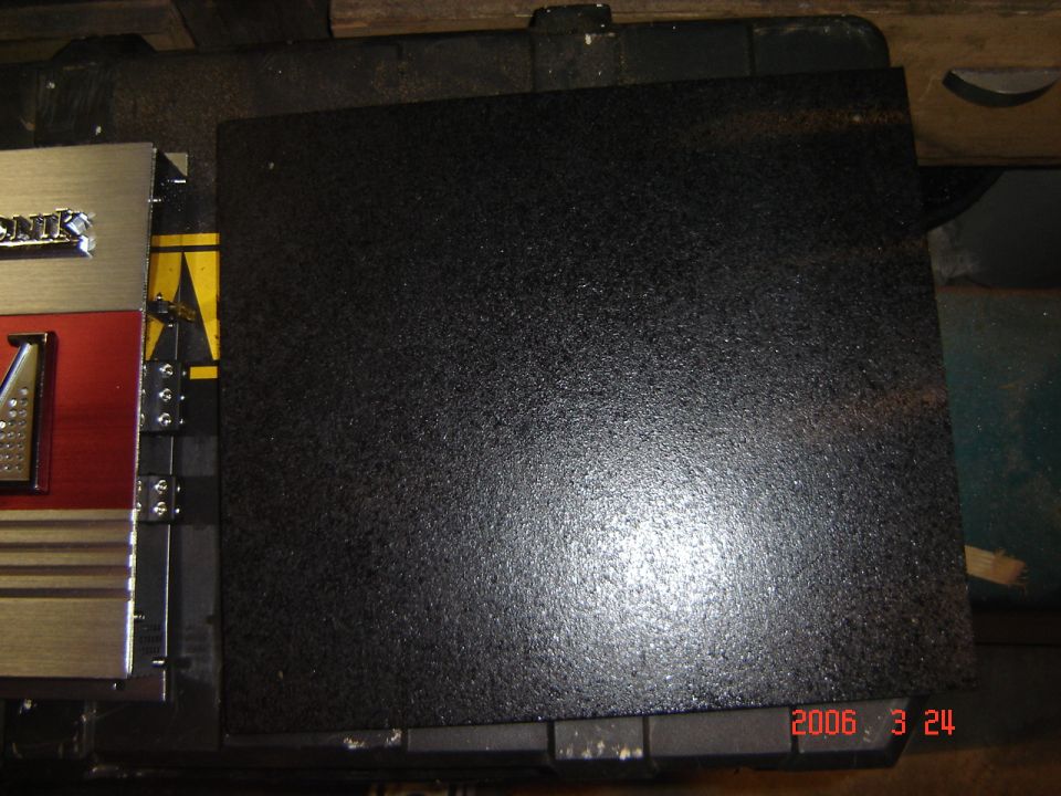 Audio amplifier with red and silver accents next to a black textured panel