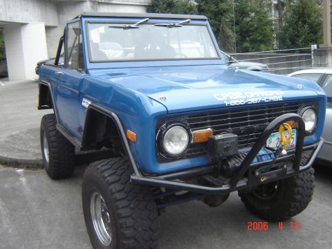 1993 Ford Bronco - This blue Ford Bronco features a winch and off-road tires, with visible text on the hood and grille.