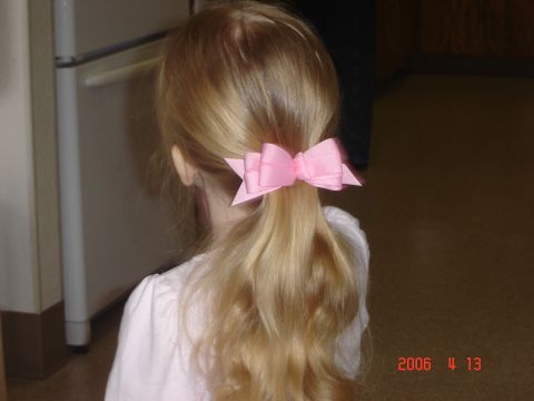 1993 Ford Bronco - A young child's back is shown, their blonde hair tied with a pink bow.